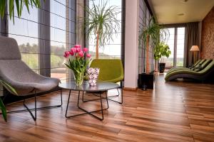 a living room with two chairs and a table with flowers at Hotel Atut w Licheniu in Licheń