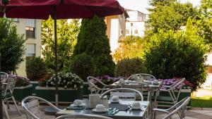 eine Terrasse mit Tischen, Stühlen und einem Sonnenschirm in der Unterkunft Goldenes Theater Hotel Salzburg in Salzburg