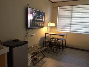 a living room with a table and a television on the wall at GOLDEN PEAK CONDO in Cebu City