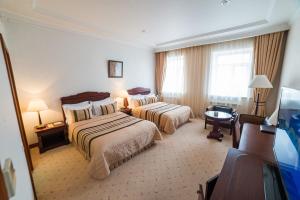 トムスクにあるMagistrat Hotelのベッド2台とデスクが備わるホテルルームです。