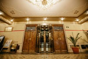 a lobby with two wooden doors and a chandelier at Hotel KARAVAN in Urganch +37 photos