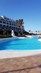 una piscina de agua azul frente a un hotel en Rocas del Mar Tenerife, en Costa del Silencio