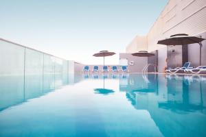 a pool with chairs and umbrellas in a building at Treppan Hotel & Suites By Fakhruddin in Dubai