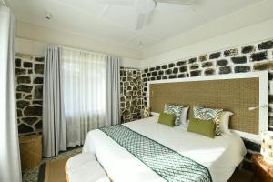 1 dormitorio con cama y pared de piedra en Kaz'alala Hosted B&B, en Bel Ombre