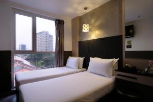 duas camas em um quarto de hotel com janela em The Snooze Hotel at Bugis em Singapura