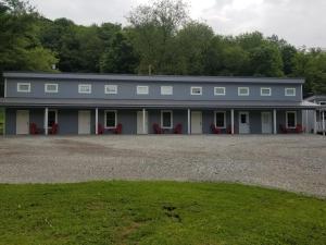 un gran edificio blanco con sillas rojas delante en Sunset Cottage Motel Rooms, en Ligonier