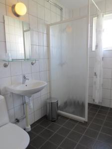 a white bathroom with a sink and a shower at Hotel Laurenti in Söderköping
