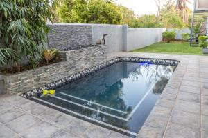 a swimming pool in a backyard with a stone retaining wall at Tzaneen Arborpark Lodge in Tzaneen