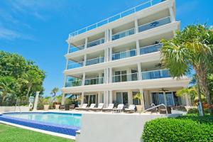 a large white building with a swimming pool and palm trees at Sea Breeze, Grand Cayman in West Bay