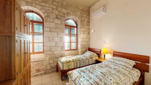 a bedroom with two beds and two windows at HEMDAT NEFESH in Safed