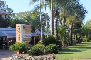 a sign in front of a resort with palm trees at Rainbow Sands Resort in Rainbow Beach