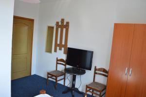 um quarto com uma televisão e duas cadeiras e um armário em Motel Signal em Banja Luka
