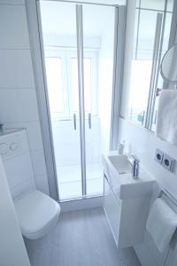 ein weißes Bad mit einem WC und einem Waschbecken in der Unterkunft Kuschelkajüte by WellenRausch in Travemünde