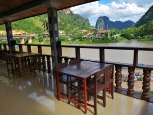 a table and chairs on a balcony overlooking a river at Arthith Guesthouse in Nongkhiaw