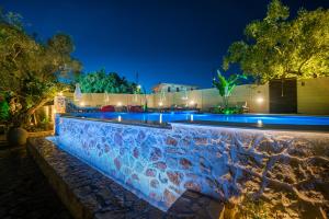 una piscina por la noche con luces azules en Ktima Kourou en Tragaki