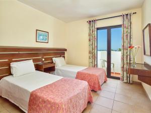 a hotel room with two beds and a balcony at Cheerfulway Ouravista Apartamentos in Albufeira