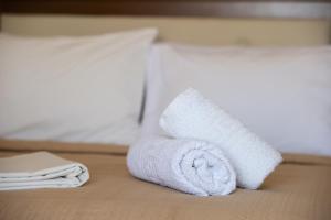 a white towel laying on top of a white bed at Hotel Stefani in Sarti