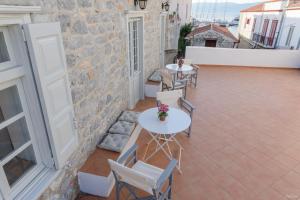 a patio with two tables and chairs on a building at Astraea in Hydra