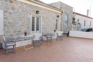 a patio with tables and chairs in front of a stone building at Astraea in Hydra