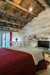1 dormitorio con 1 cama grande y pared de piedra en Corte del Merlo en Palermo