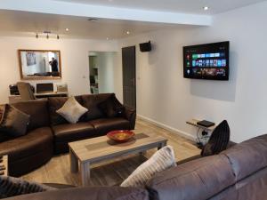 a living room with couches and a tv on the wall at Dobbies Adults Only Boutique Apartment in Saint-Marcel