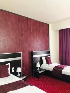 a hotel room with two beds and a red wall at Hotel Angellis in Timişoara