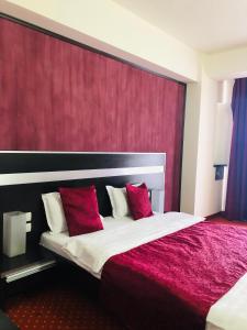 una habitación de hotel con una cama grande con almohadas rojas en Hotel Angellis, en Timisoara