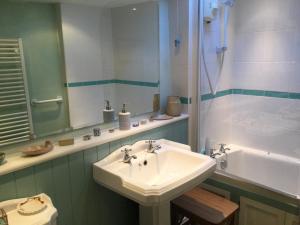 La salle de bains est pourvue d'un lavabo, d'une douche et d'une baignoire. dans l'établissement Jasmine Cottage, à Lerryn