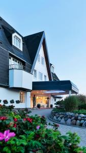 a large white house with a balcony and flowers at Dorint Strandresort & Spa Westerland/Sylt in Westerland