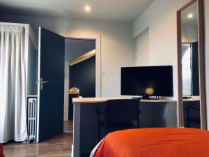 a bedroom with a bed and a desk with a television at Hotel Linette in Aumont-Aubrac