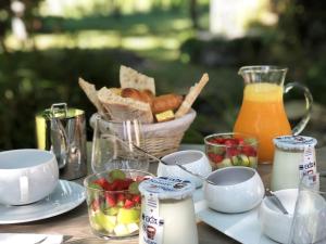 una mesa con comida y una cesta de fruta y zumo en La Gomerie Chambres d'Hotes, en Saint-Émilion
