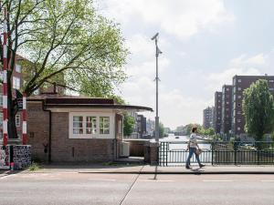 a woman walking down a street next to a building at SWEETS - Van Hallbrug in Amsterdam