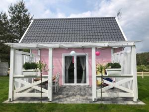 ein rosafarbenes Haus mit einem weißen Pavillon in der Unterkunft Bajkowy domek Villa Rosa na Kaszubach in Grzybowo