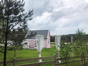 ein rosa Haus auf einem Feld mit einem Zaun in der Unterkunft Bajkowy domek Villa Rosa na Kaszubach in Grzybowo
