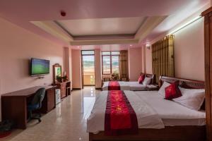 une chambre d'hôtel avec deux lits et un bureau dans l'établissement KHÁCH SẠN SEN VÀNG, à Lào Cai
