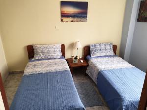 two twin beds in a room with a table at Tolis Apartments in Preveza