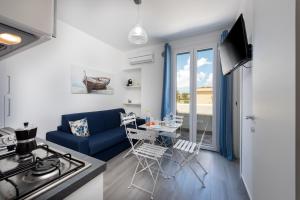 a living room with a blue couch and a table with chairs at Isule Apartments in San Vito lo Capo