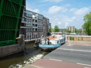 a boat is docked in a river next to buildings at SWEETS - Van Hallbrug in Amsterdam +9 photos