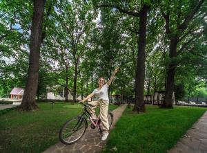 a woman riding a bike in a park at Optima Collection Aquadar in Manʼkivka