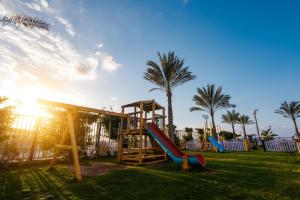 a playground with slides and palm trees in a park at Tolip Family Club Borg El Arab in King Mariout