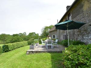 um pátio com um guarda-sol, uma mesa e cadeiras em Charming holiday home in a green setting em Montaigu-les-Bois