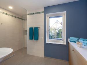 a bathroom with a blue wall and a window at Appartements Bank am See in Immenstaad am Bodensee