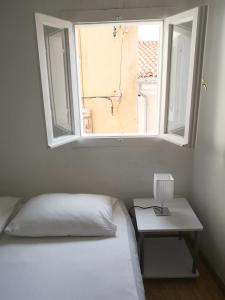 ein Schlafzimmer mit einem Bett und einem Tisch mit einem Fenster in der Unterkunft Tiny room in Piran