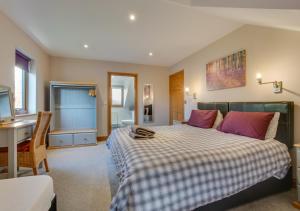 a bedroom with a bed with pink pillows and a desk at Corlan Aber in Rhyd-y-felin