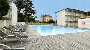 a swimming pool with chairs on a wooden deck at Vacancéole - Le Domaine du Château - La Rochelle / Île de Ré in Lagord