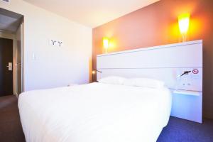 a hotel room with a large white bed with two pillows at Kyriad La Rochelle Centre - Les Minimes in La Rochelle