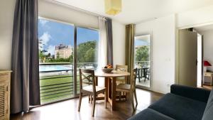 un salon avec une table et une grande fenêtre dans l'établissement Vacancéole - Le Domaine du Château - La Rochelle / Île de Ré, à Lagord