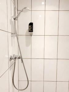 a shower in a bathroom with white tiles at Hostel The Globe in Amsterdam