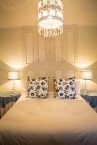 a bedroom with a bed with two lamps and a chandelier at Silver Linings Guesthouse in Parys