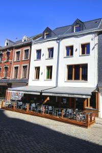 a white building with tables and chairs on a street at ô ChÔmière in Stavelot